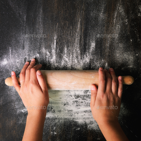 Girl hands keep rolling pin with flour on dark black table, baking background, top view, copy space - Stock Photo - Images