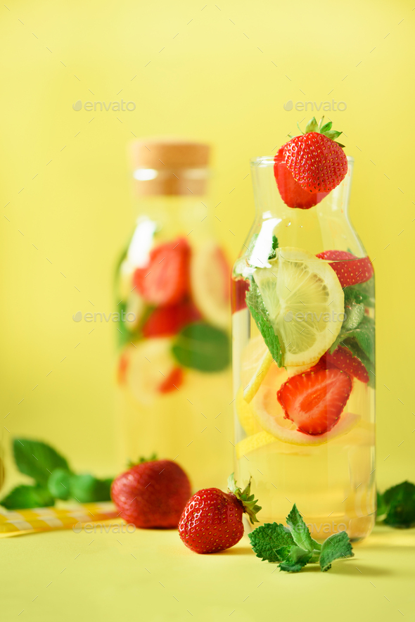 Fresh fruit flavored water with strawberry, lemon, mint on yellow background. Summer drink concept - Stock Photo - Images