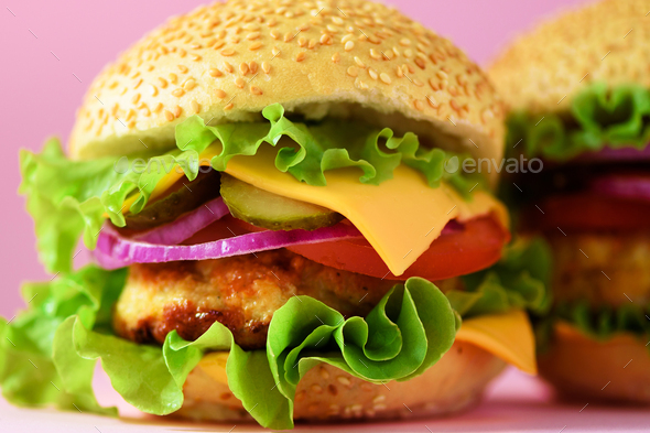 Macro view of tasty burger with beef, cheese, lettuce, onion, tomatoes on yellow background. Close - Stock Photo - Images