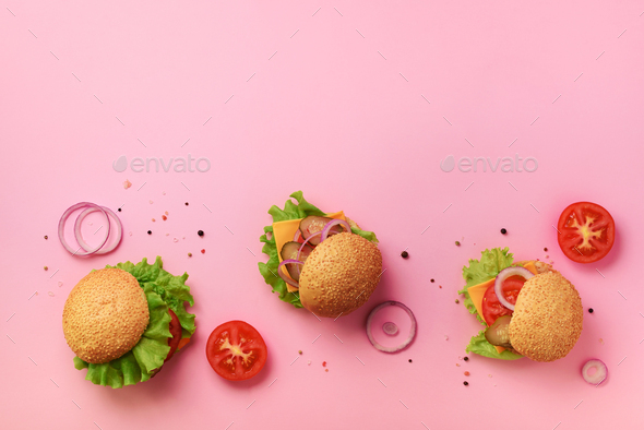 Tasty burgers with beef, tomato, cheese, onion, cucumber and lettuce on pink background. Top view - Stock Photo - Images