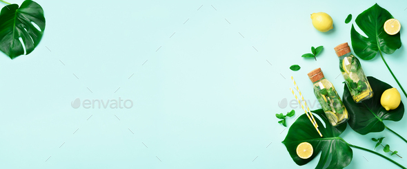 Bottle of detox water with mint, lemon and tropical monstera leaves on blue background. Flat lay - Stock Photo - Images