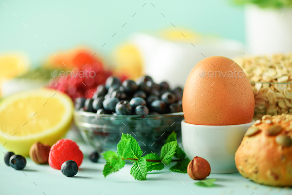 Breakfast served with soft boiled egg, oat flakes, nuts, fruits, berries, milk, yogurt, orange - Stock Photo - Images