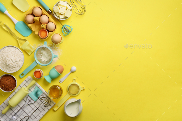 Butter, sugar, flour, eggs, oil, spoon, rolling pin, brush, whisk, towel over yellow background - Stock Photo - Images