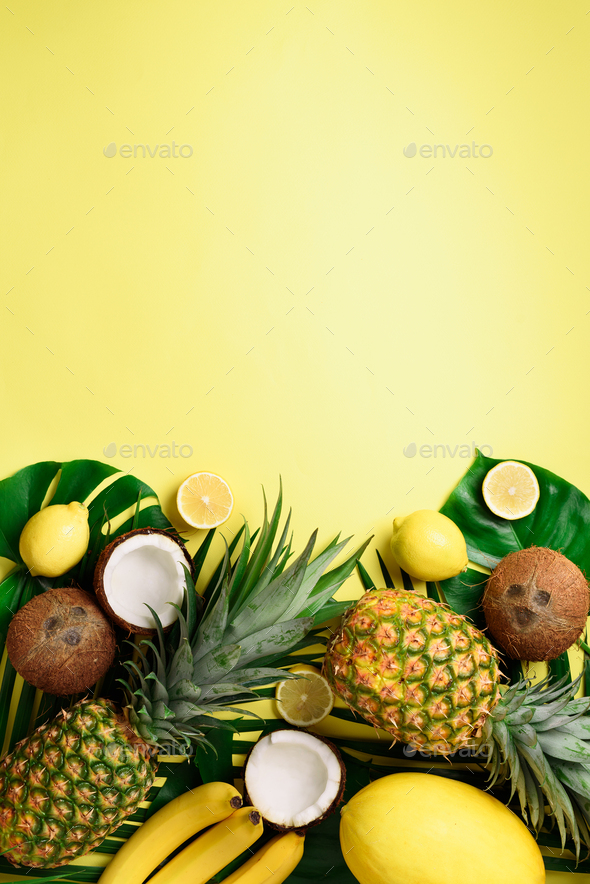 Exotic pineapples, ripe coconuts, banana, melon, lemon, tropical palm and green monstera leaves on - Stock Photo - Images