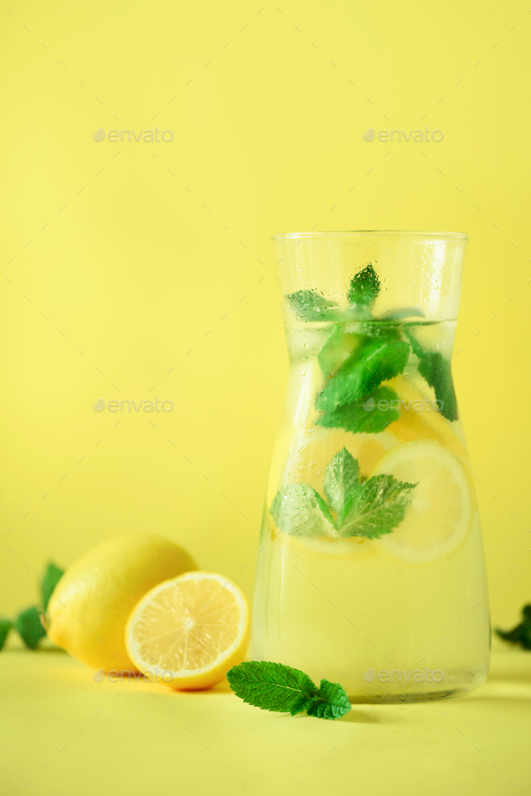 Fresh summer fruits water or lemonade with mint, ice, lemon on yellow background. Copy space. Summer - Stock Photo - Images