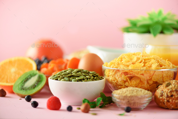 Corn flakes with milk, pumpkin seeds, fresh berries, yogurt, boiled egg, nuts, fruits, orange - Stock Photo - Images