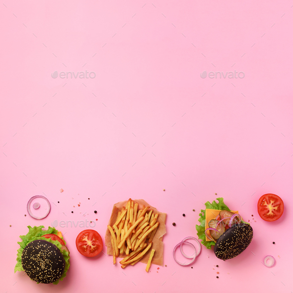 Black burger, french fries potatoes, tomatoes, cheese, onion, cucumber and lettuce on pink - Stock Photo - Images