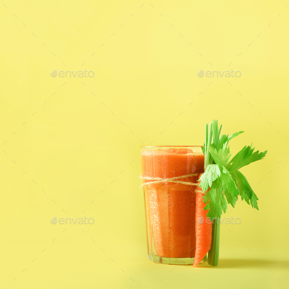 Orange carrot juice with carrots, celery on yellow background. Square crop. Fresh vegetable smothie - Stock Photo - Images