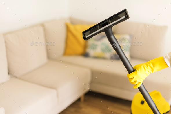 Woman cleaning sofa with yellow vacuum cleaner. Copy space. Clean concept