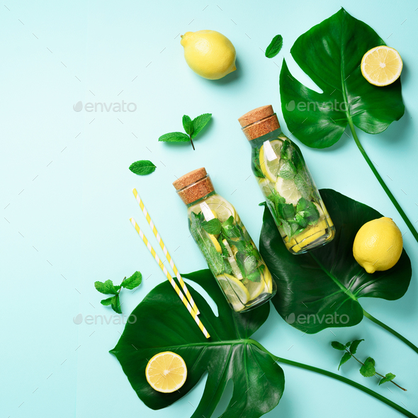 Bottle of detox water with mint, lemon and tropical monstera leaves on blue background. Square crop - Stock Photo - Images