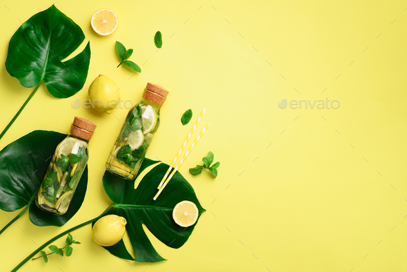Bottle of detox water with mint, lemon and tropical monstera leaves on yellow background. Flat lay - Stock Photo - Images