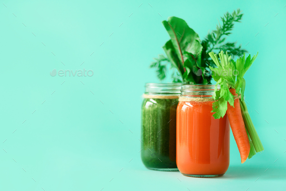 Healthy organic green and orange smoothies on blue background. Detox drinks in glass jar from - Stock Photo - Images