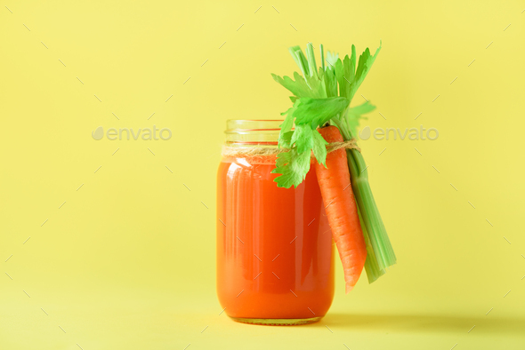 Organic carrot juice with carrots, celery on yellow background. Vegetable smothie in glass jar. Copy - Stock Photo - Images