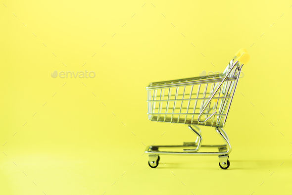 Shopping cart on yellow background. Minimalism style. Creative design. Copy space. Shop trolley at