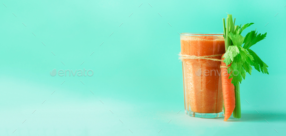 Organic carrot juice with carrots, celery on blue background. Fresh vegetable smothie in glass - Stock Photo - Images