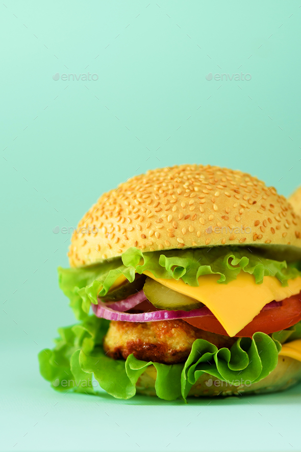 Macro view of tasty burger with beef, cheese, lettuce, onion, tomatoes on blue background. Close up - Stock Photo - Images