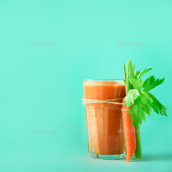 Fresh organic carrot juice with carrots, celery on blue background. Square crop. Vegetable smothie - Stock Photo - Images