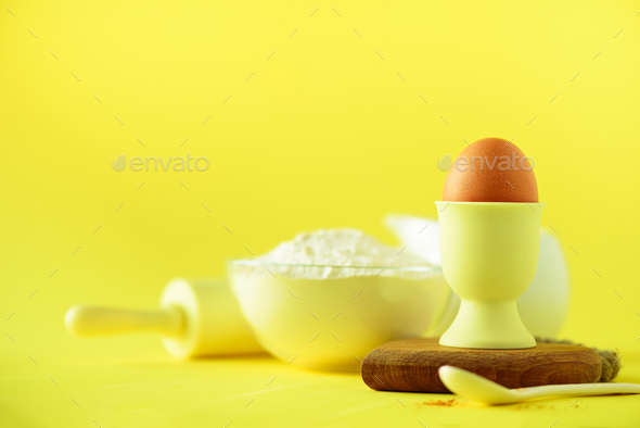Healthy baking ingredients - butter, sugar, flour, eggs, oil, spoon, rolling pin milk over yellow - Stock Photo - Images