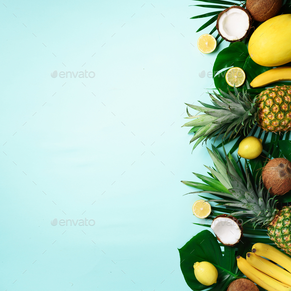 Exotic pineapples, ripe coconuts, banana, melon, lemon, tropical palm and monstera leaves on blue - Stock Photo - Images