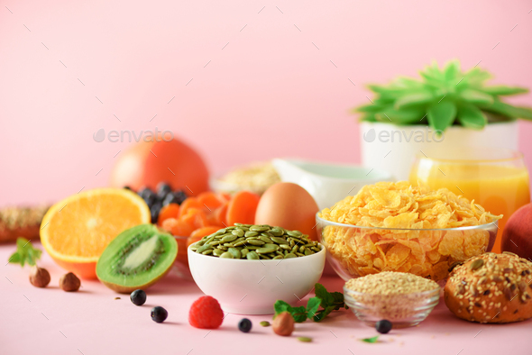 Corn flakes with milk, fresh berries, yogurt, boiled egg, nuts, fruits, orange, banana, peach for - Stock Photo - Images