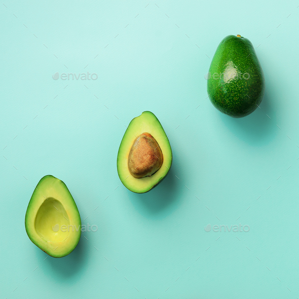 Organic avocado with seed, avocado halves and whole fruits on blue background. Top view. Pop art - Stock Photo - Images
