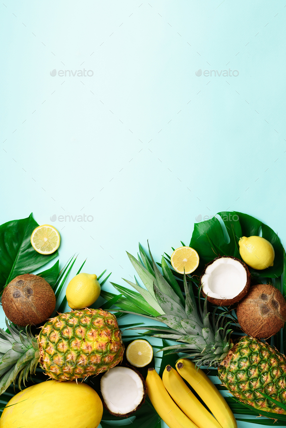 Exotic pineapples, ripe coconuts, banana, melon, lemon, tropical palm and green monstera leaves on - Stock Photo - Images