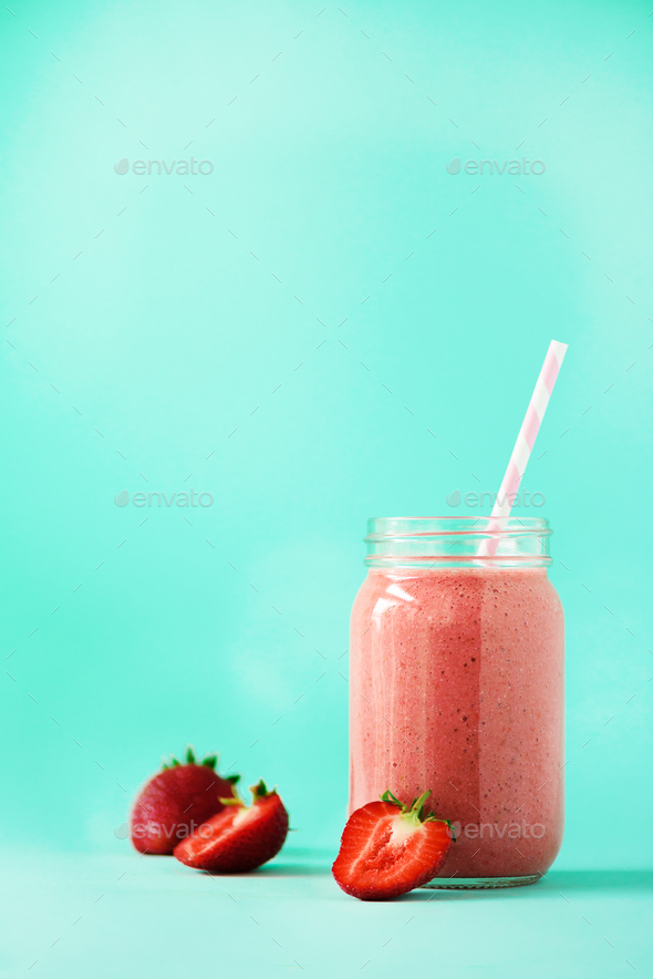Pink strawberry milkshake in glass jar on blue background with copy space. Summer food concept - Stock Photo - Images