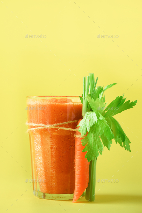 Organic carrot juice with carrots, celery on yellow background. Fresh vegetable smothie in glass - Stock Photo - Images