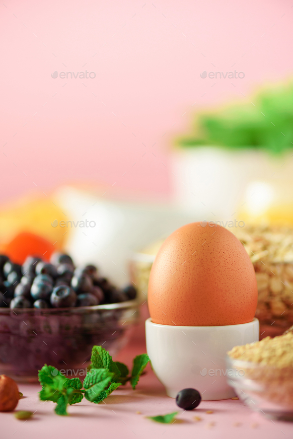 Delicious breakfast ingredients. Soft boiled egg, oat flakes, nuts, fruits, berries, milk, yogurt - Stock Photo - Images