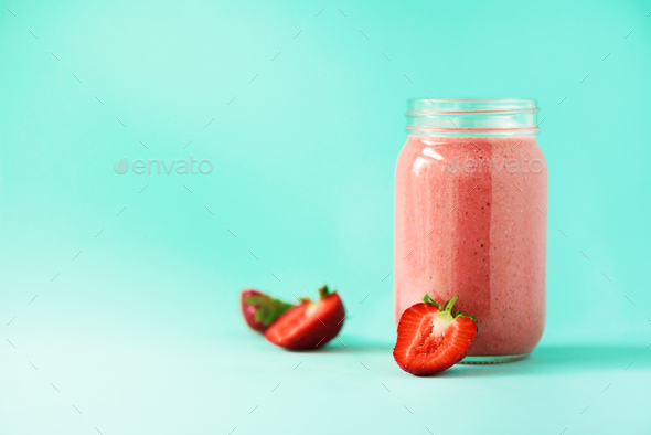 Pink strawberry milkshake in glass jar on blue background with copy space. Summer food concept - Stock Photo - Images