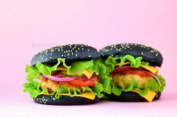 Unhealthy black burgers with beef, cheese, lettuce, onion, tomatoes on pink background. Take away - Stock Photo - Images