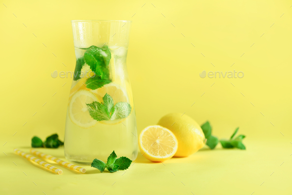 Fresh summer fruits water or lemonade with mint, ice, lemon on yellow background. Copy space. Summer - Stock Photo - Images
