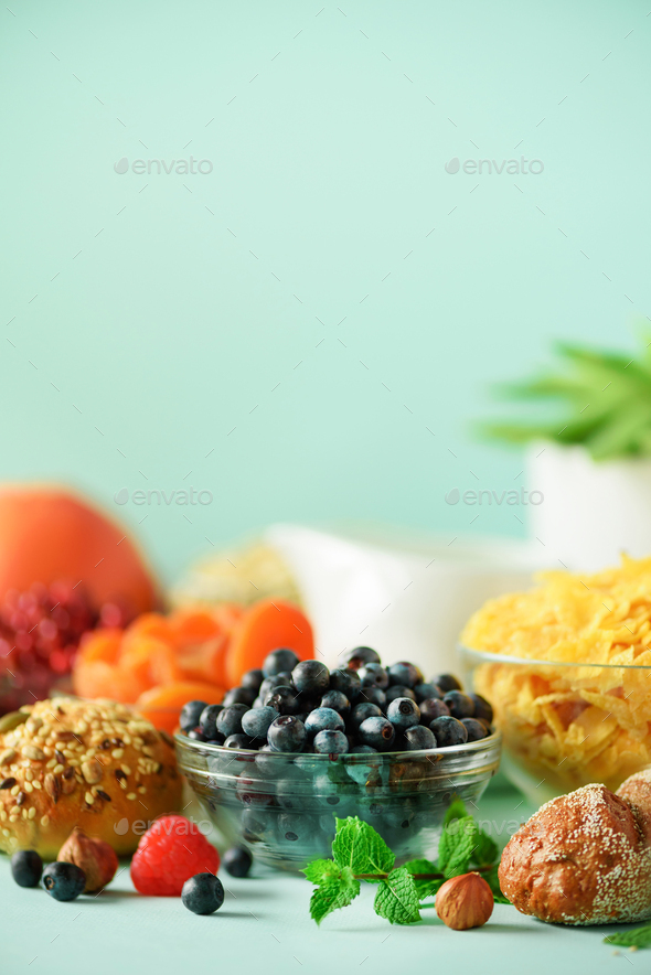 Delicious breakfast ingredients. Corn flakes, nuts, fruits, berries, milk, yogurt, orange, banana - Stock Photo - Images