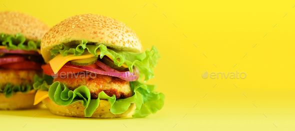 Fast food banner. Juicy meat burgers with cheese, lettuce on yellow  background. Take away meal Stock Photo by jchizhe