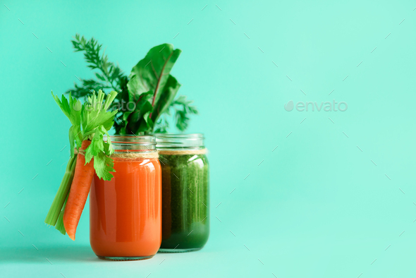 Healthy organic green and orange smoothies on blue background. Detox drinks in glass jar from - Stock Photo - Images
