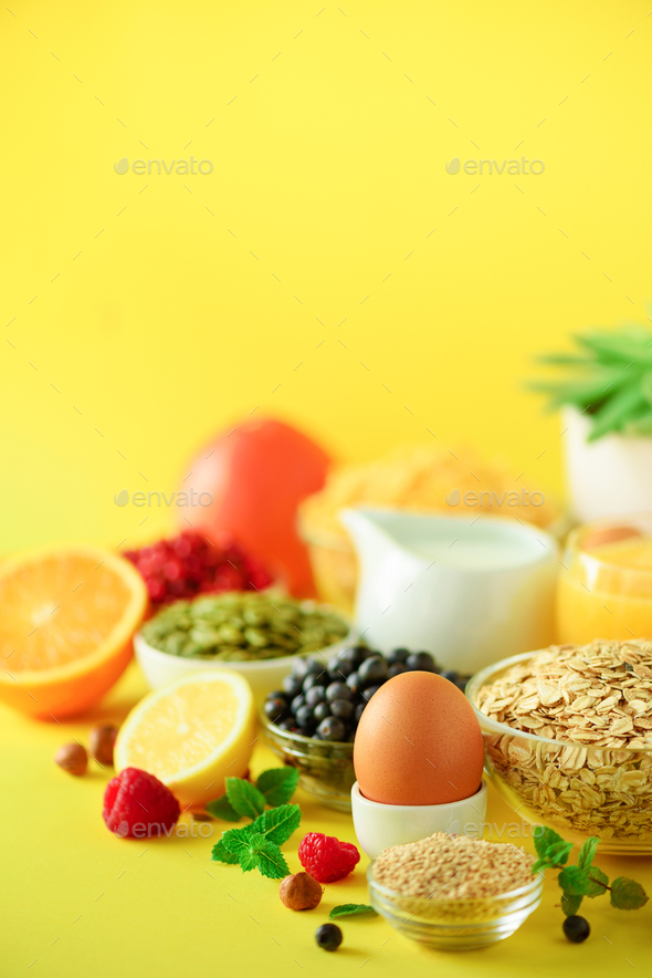 Breakfast served with soft boiled egg, oat flakes, nuts, fruits, berries, milk, yogurt, orange - Stock Photo - Images