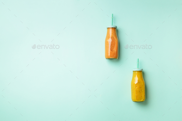 Fresh orange, banana, pineapple, mango smoothies and juicy fruits on blue background. Detox summer - Stock Photo - Images