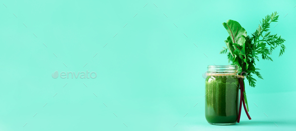 Banner of green smoothie with leafy beet greens and carrot tops on blue background, copy space - Stock Photo - Images