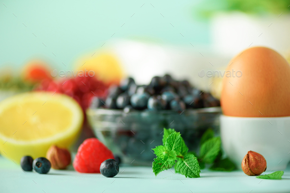 Delicious breakfast ingredients. Soft boiled egg, oat flakes, nuts, fruits, berries, milk, yogurt - Stock Photo - Images