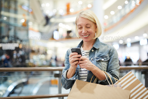 Happy woman texting sms in shopping mall - Stock Photo - Images