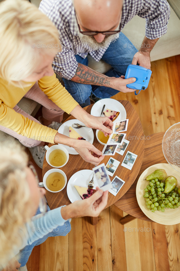 Mature friends watching polaroid images - Stock Photo - Images