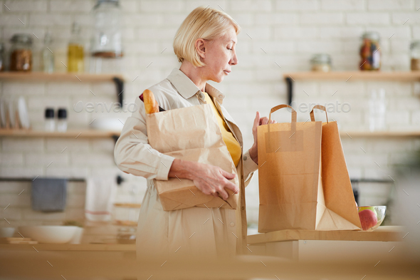 Mature woman coming home after shopping in grocery store - Stock Photo - Images