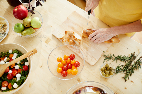 Cutting baguette on wooden board - Stock Photo - Images