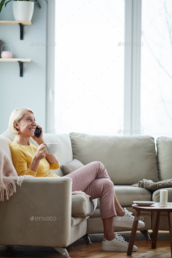 Woman talking on phone in living room - Stock Photo - Images