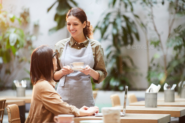 Attractive waitress serving coffee to guest - Stock Photo - Images