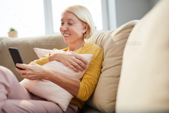 Cheerful lady reading message on phone - Stock Photo - Images