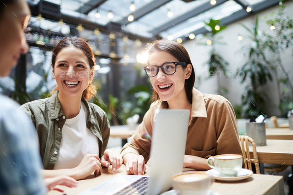 Excited colleagues working as team in cafe - Stock Photo - Images