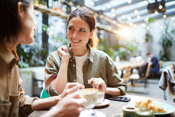 Positive women discussing last news in cafe - Stock Photo - Images