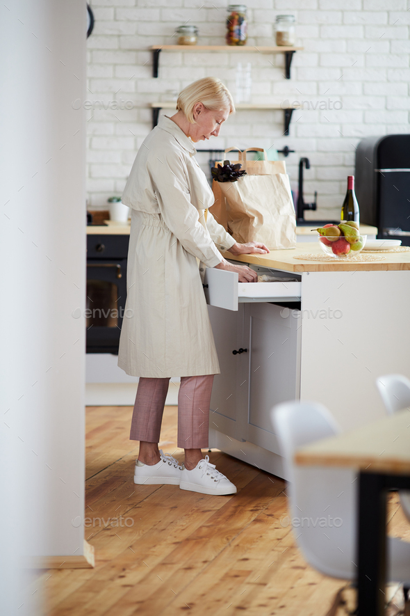 Woman finding utensil in kitchen drawer - Stock Photo - Images