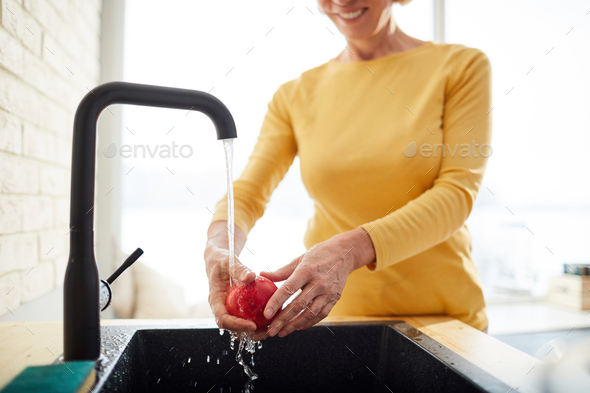Washing apple under water from tap